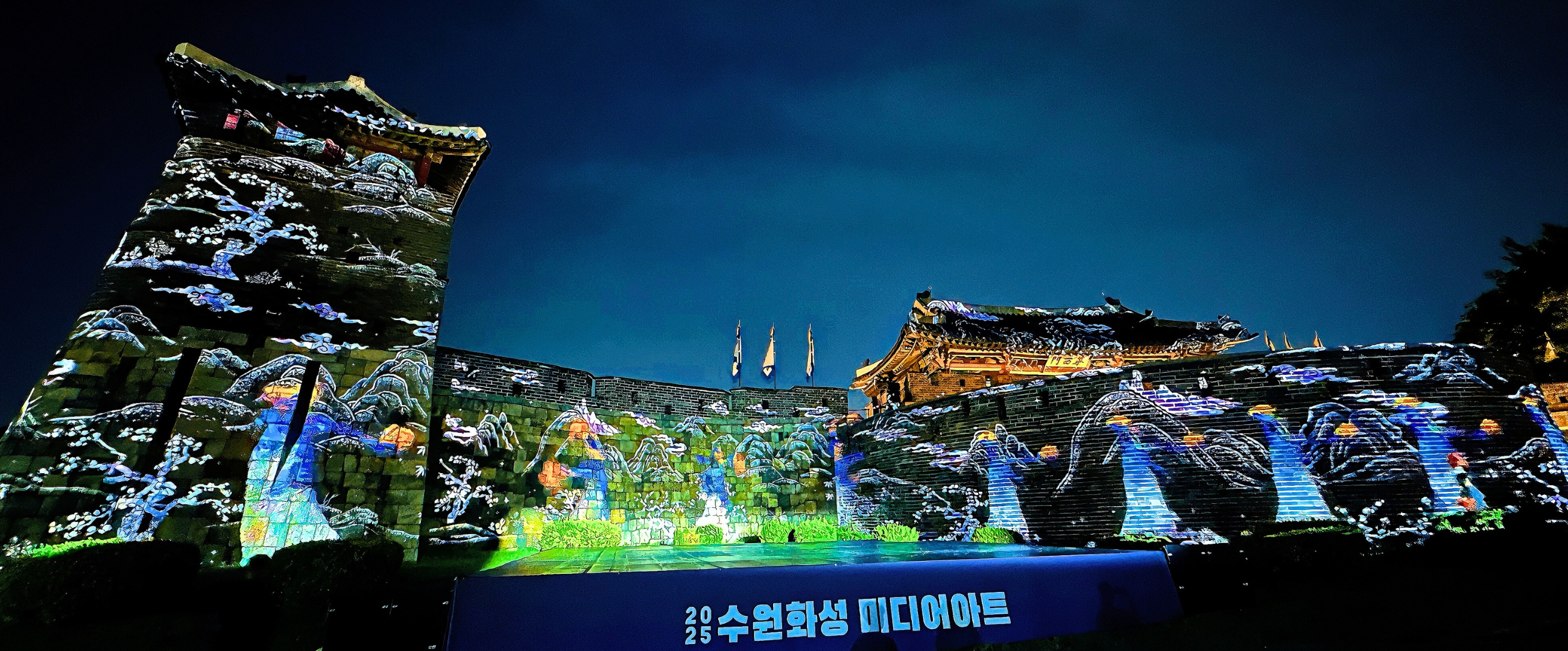 수원 화성 성곽을 스크린 삼아 펼쳐지는 화려한 미디어 아트 쇼. 다채로운 색의 조명과 패턴이 성벽을 가득 채우고 있다.