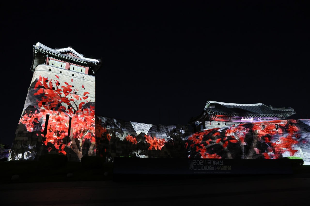 밤의 수원화성 성벽에 붉은 꽃가지 문양의 미디어 아트가 투사되고 있다.