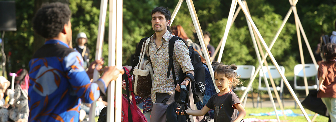 공연자가 나무에 매달려 공연을 펼치고 있는모습 주변에 관객들이 구경하고있다.