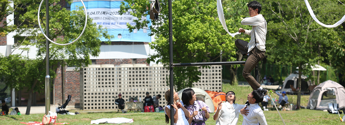 빨간코를 한 공연자들이 테이블에 앉아 정면을 보고 웃고있다